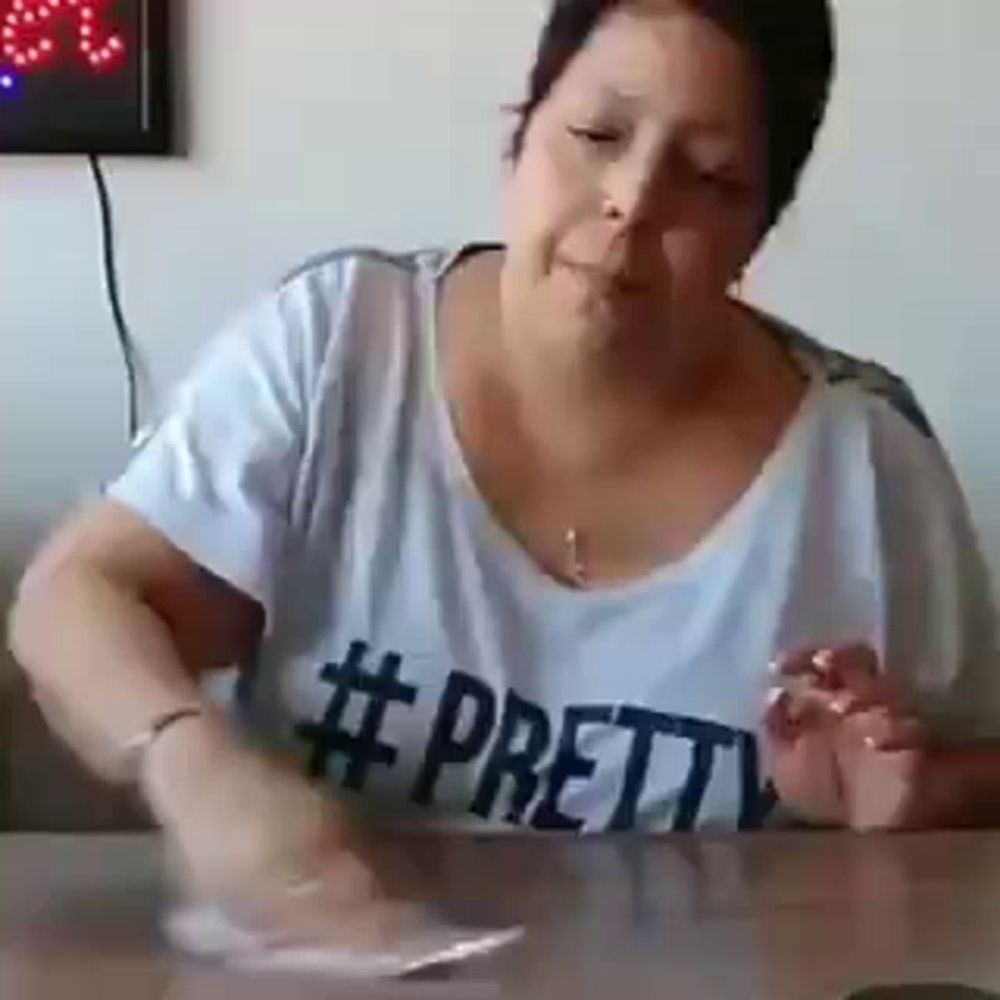 a woman in a pretty shirt is sitting at a table with a plate of food .