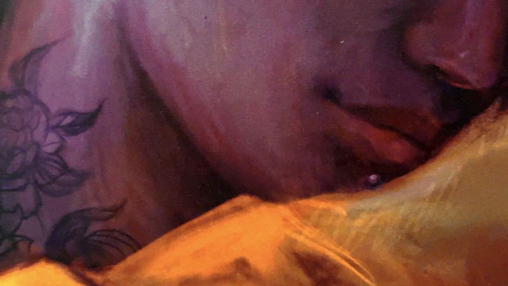 close up of a mans chin, with flower tattoos and yellow silk shirt 