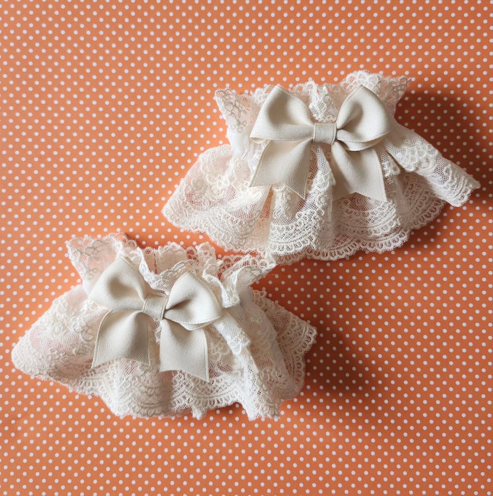 A pair of beige egl wristcuffs on an orange polkadot background. 