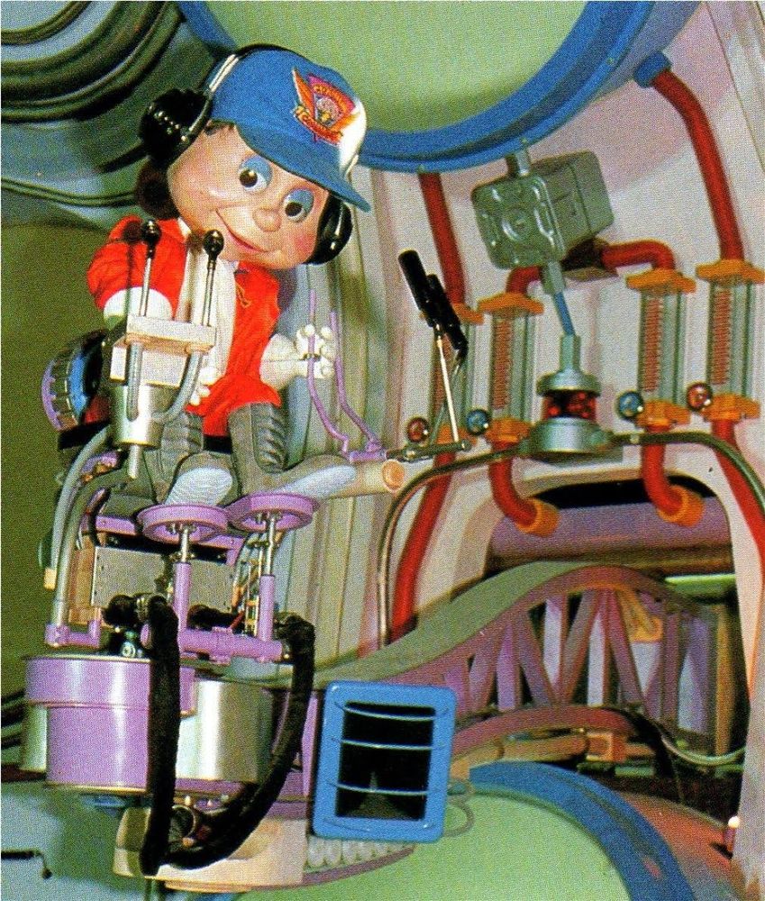 The Captain Cortex animatronic. His design mostly remained the same, but there's still some changes. His jumpsuit is more reddish, his gloves are just white, his hat has the Cranium Command logo, and his boots are grey. Other changes are the addition of brown tufts of hair and a white scarf. Strangely, in this photo he has blue eyelids. 

For the longest time, this was one of the only images of the character, since it was used in books, promos and even WDW Explorer 98.