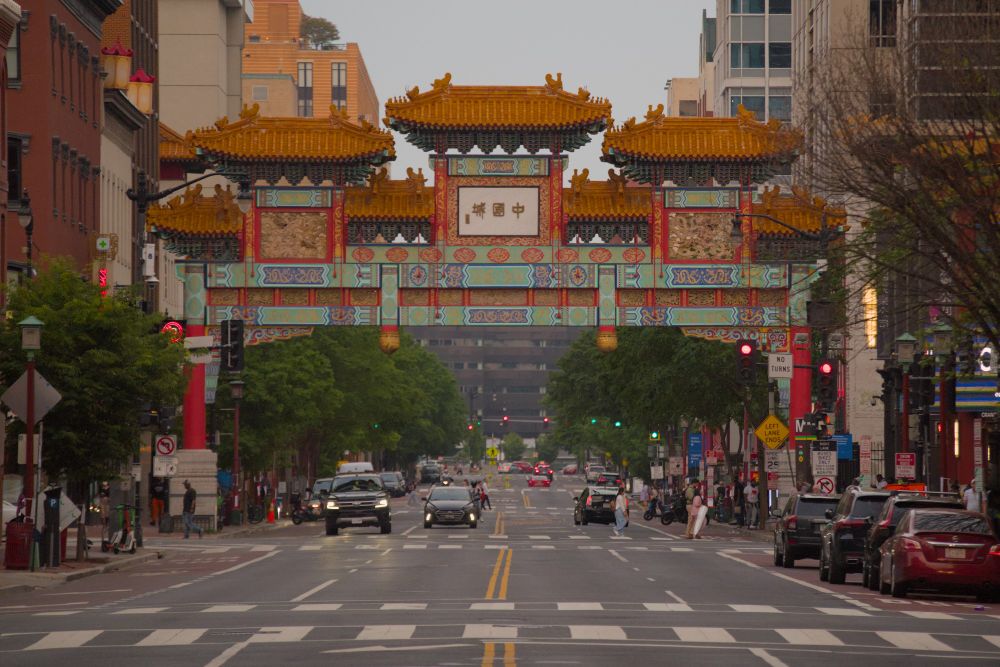 picture of the DC Chinatown Friendship Archway, which is over a street that has a few cars. the sky is cloudy.