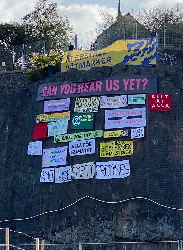 Banderoller på bergvägg vid Slussen - nu med Återställ Våtmarker utrullad högst upp