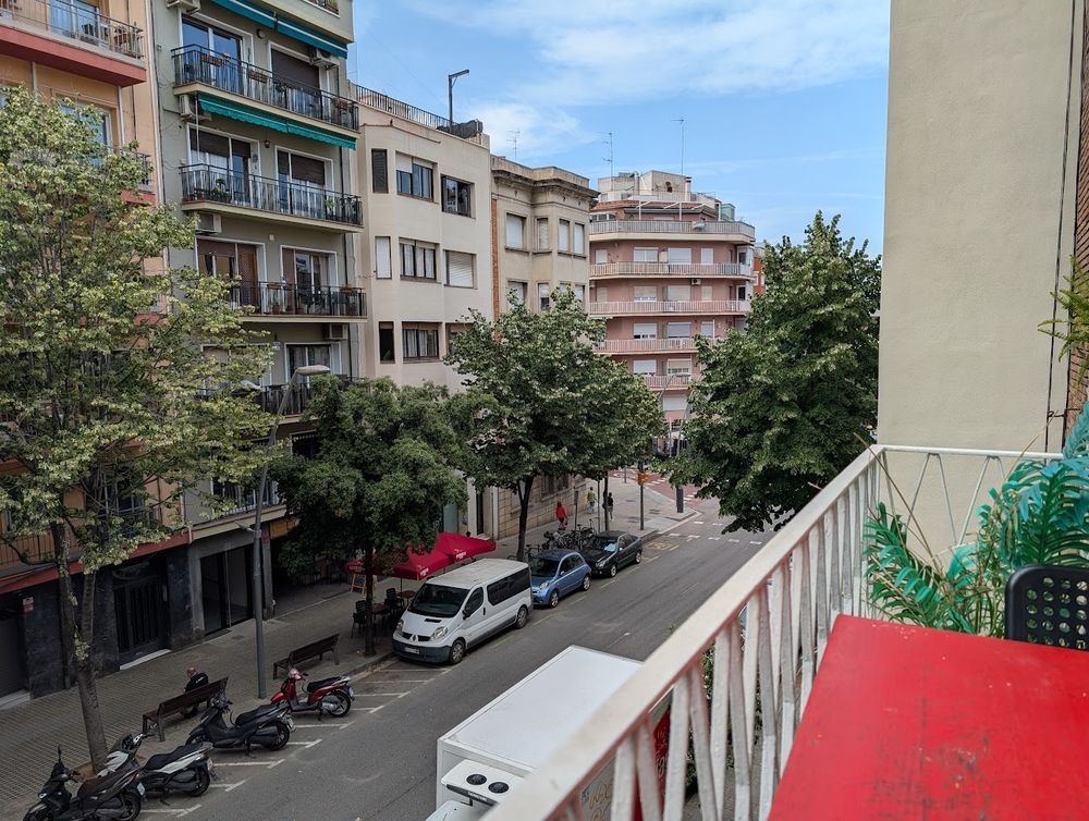 A view of the street from the balcony of my apartment in Barcelona.  Several 4-5 story buildings are visible, and a blue sky with some wispy clouds