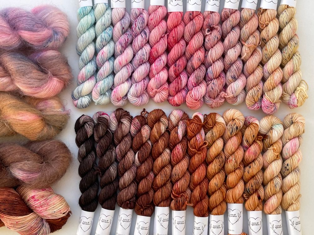 Alternative arrangement of the kit.

There are 2 rows of 12 minis in most of the photo. On the left there are 4 skeins of mohair and 1 skein of singles. 

Left to right 
The top row of minis goes from light blues to pinks and yellowish caramels

The bottom row of minis goes from dark brown to warm coppers to light caramels

The fluff and Singles skein (top to bottom) goes from pink to dusky pink to caramel to brown and final skein has a mix of dark brown and light caramel