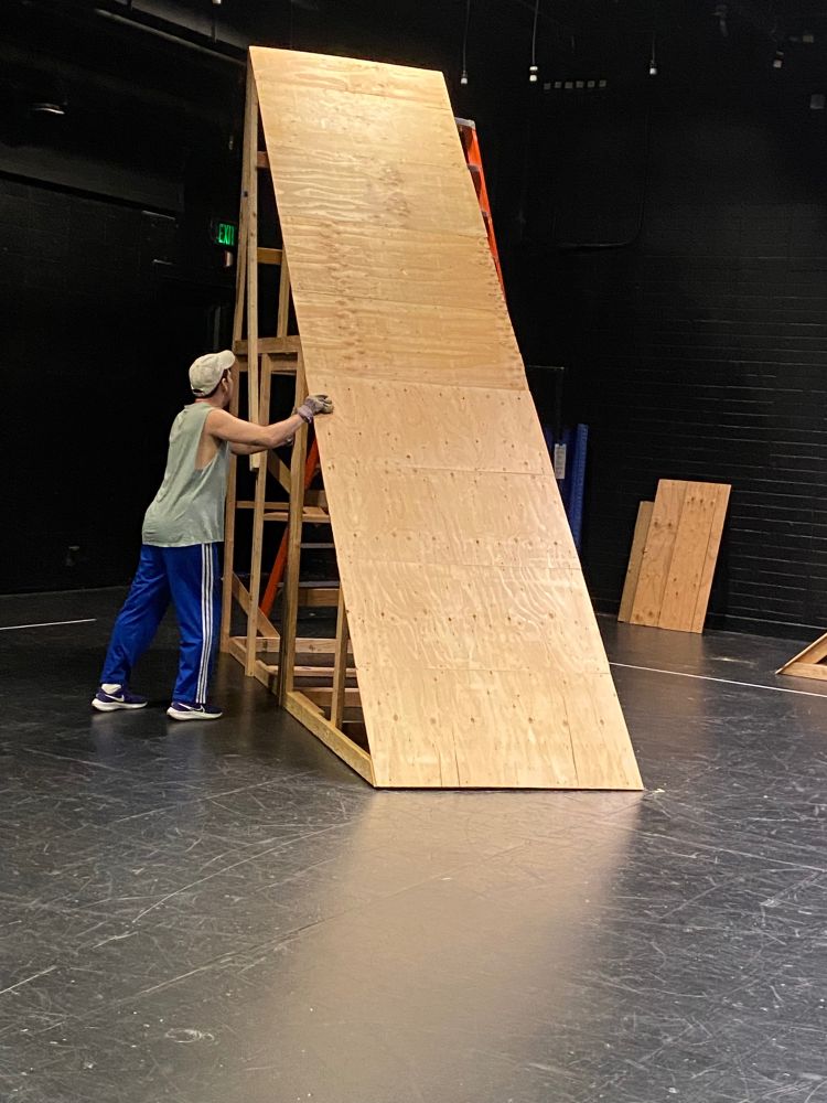 Vertiginous ramp made out of plywood with dancer preparing to move it. The ramp is used by dancers from work by Kensaku Shinohara. 