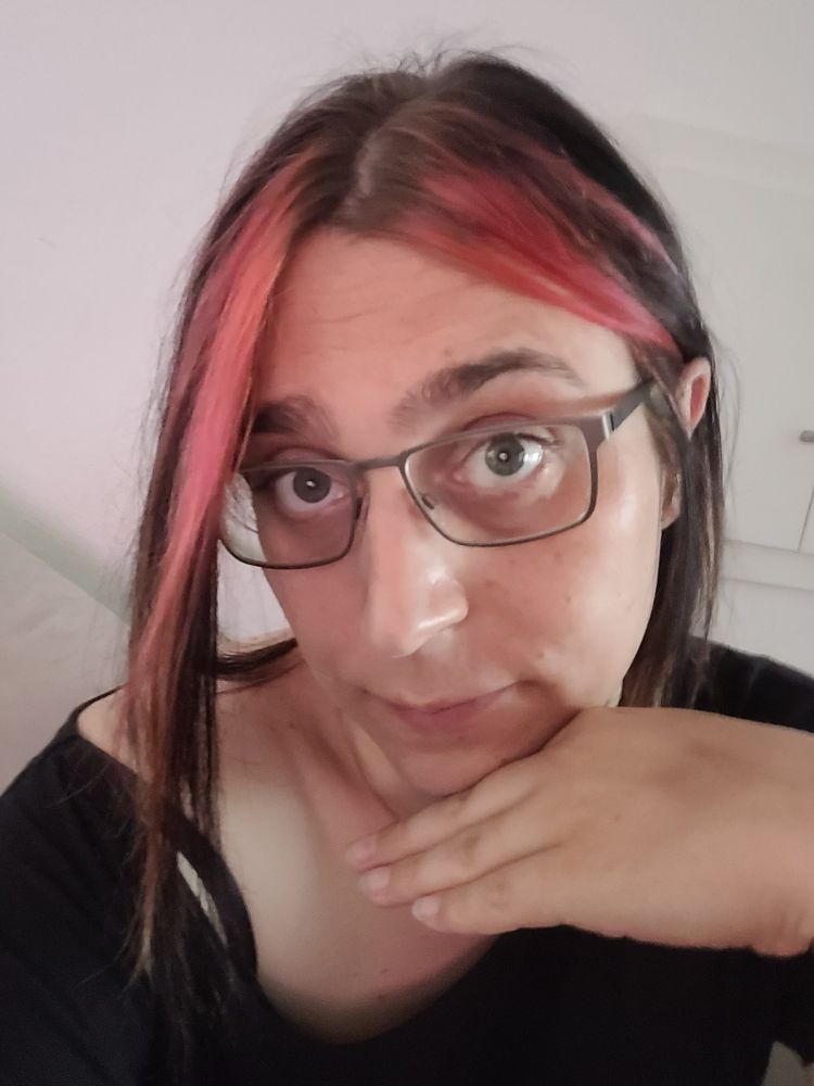 Ich schaue in die Kamera, Koof leicht geneigt und Hand unterm Kinn.