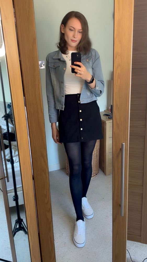 Woman in a black shirt, black tights, white trainers and a white top with a blue denim jacket