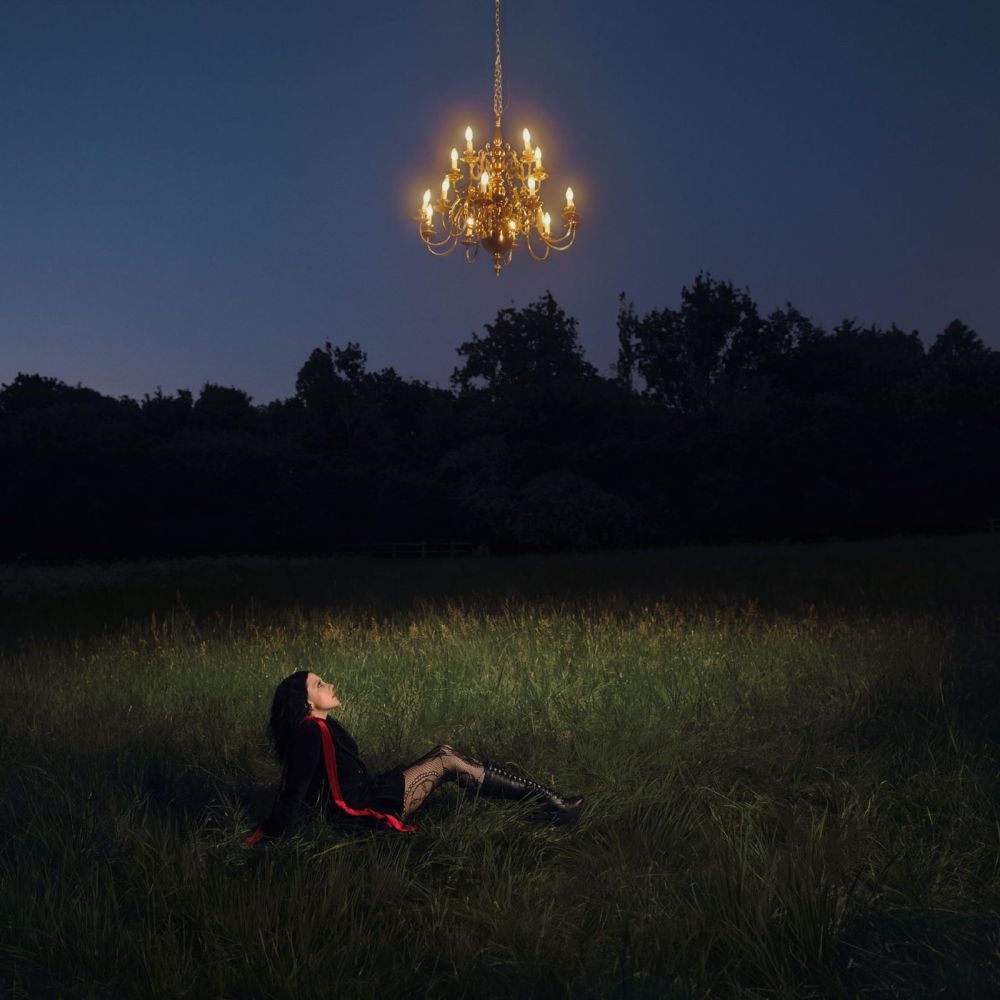 Woman sat on the ground looking up at a chandelier
