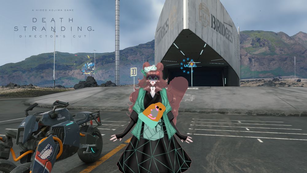 An angry Em in the middle, or maybe serious, as she stands in front of a Bridges building, with the logo for Death Stranding in the background as she stands near a reverse-trike.