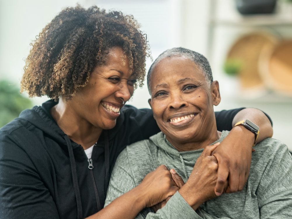 Two people smiling and embracing warmly in a home setting.