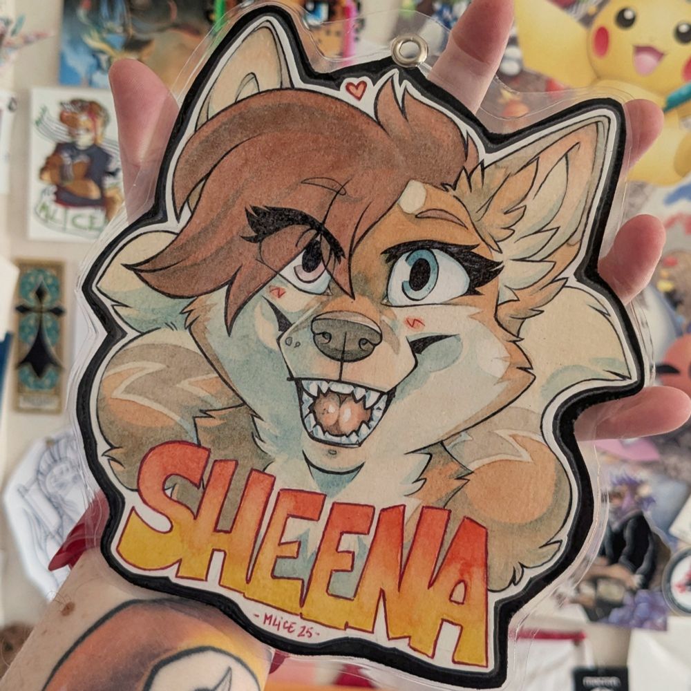 Watercoloured convention's badge for Sheena, a red haired vixen with two tails