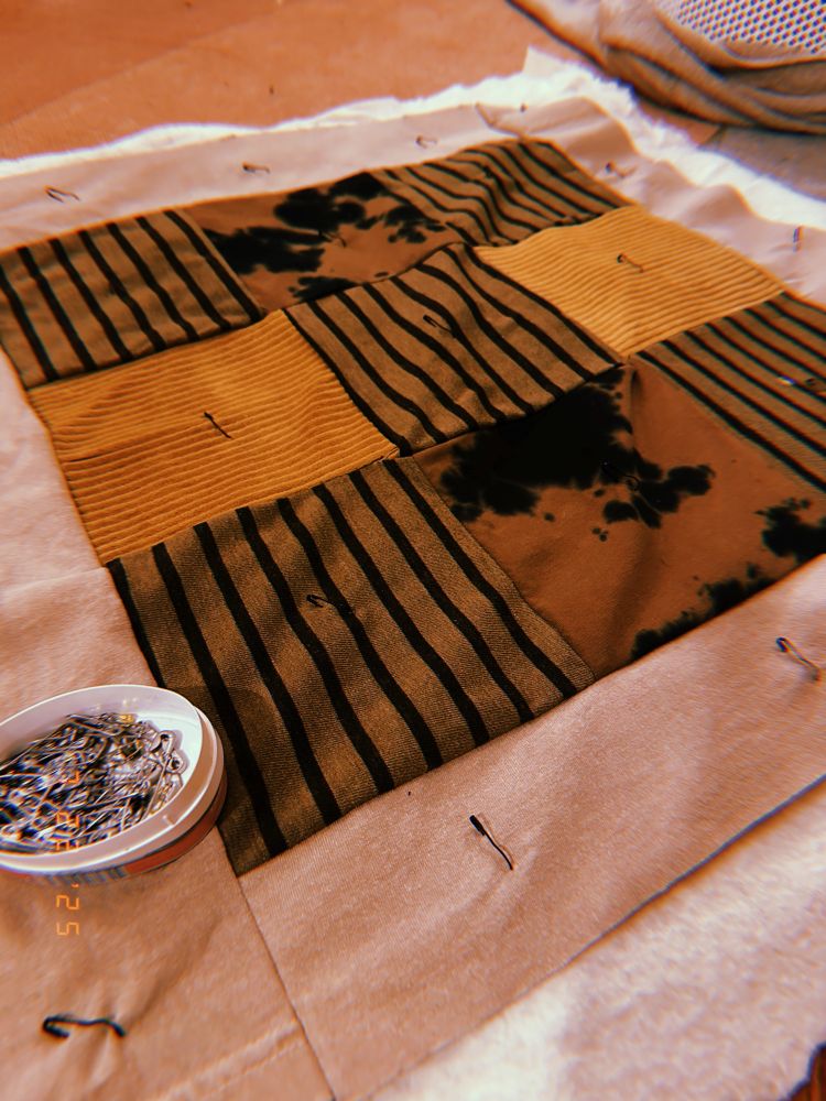an assembled quilt with safety pins holding it together every 5-ish inches 