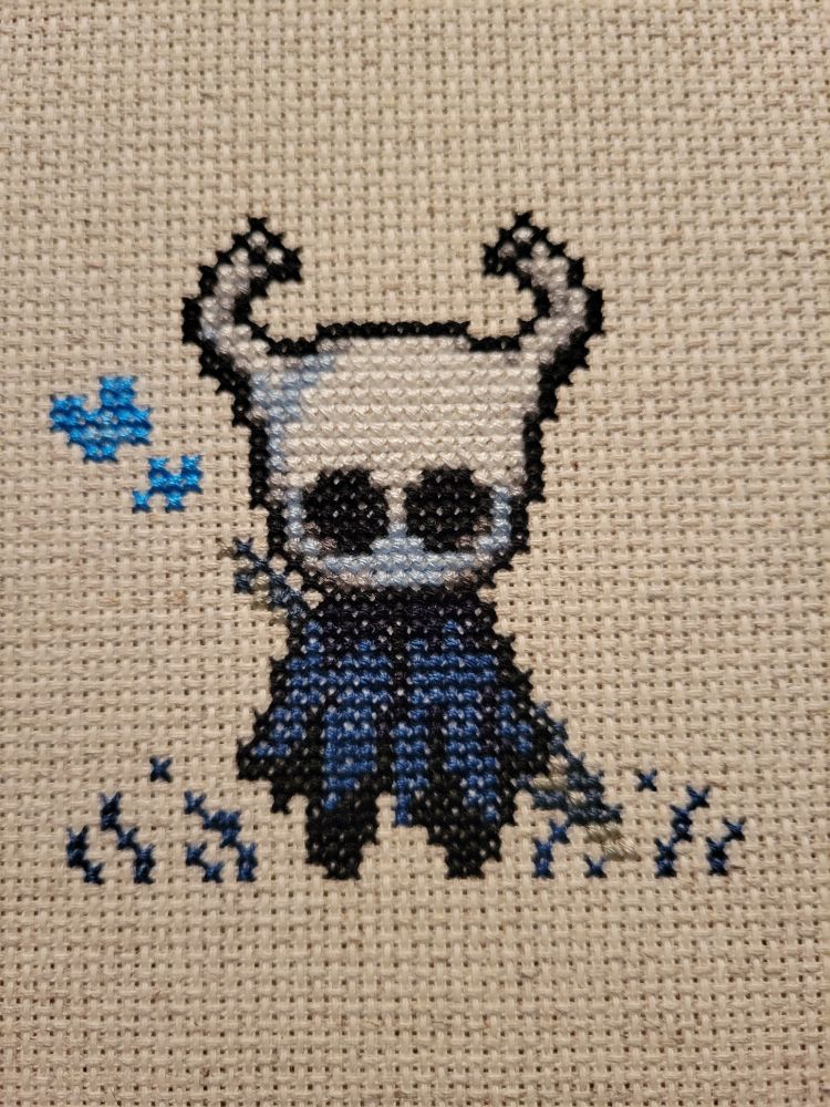 A finished cross stitch of the knight from hollow knight.