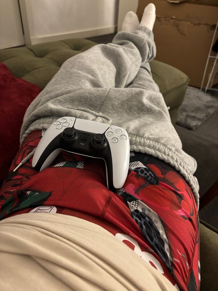 White Playstation controller sitting on lap, whilst resting across a chaise sofa, theme in response to the Lunar New Year