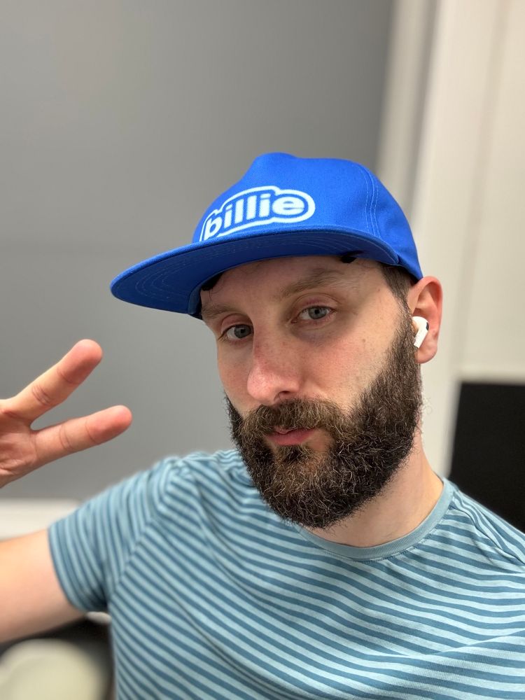 Just me with a blue Billie Eilish tour cap on in my kitchen after her concert earlier in the evening. I am doing a peace sign with my right hand