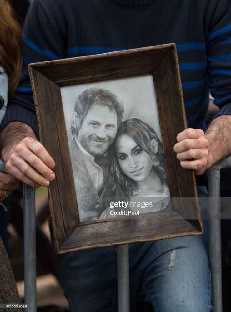 A man holding a pencil drawing(in a frame) of Harry Sherran and Megs Marks. They're hobbits.