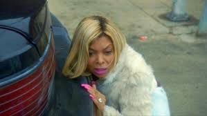 Cookie Lyon hiding behind a car