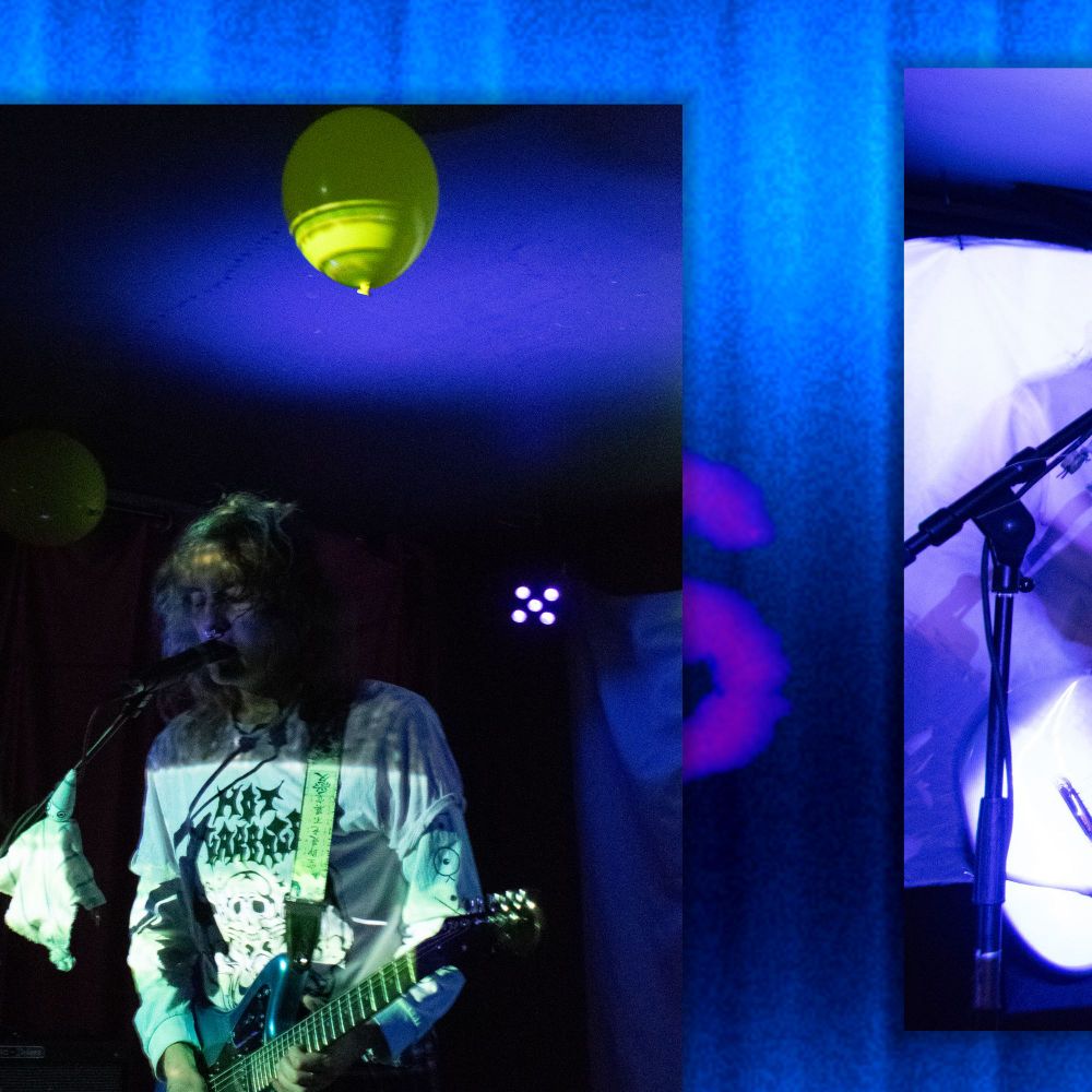 Photo de moi en train chanter et jouer de la guitare à un concert. L'ambiance est assez sombre, dans les teintes violettes avec quelques zones verdâtres. Un ballon d'hélium jaune brille sur le plafond.