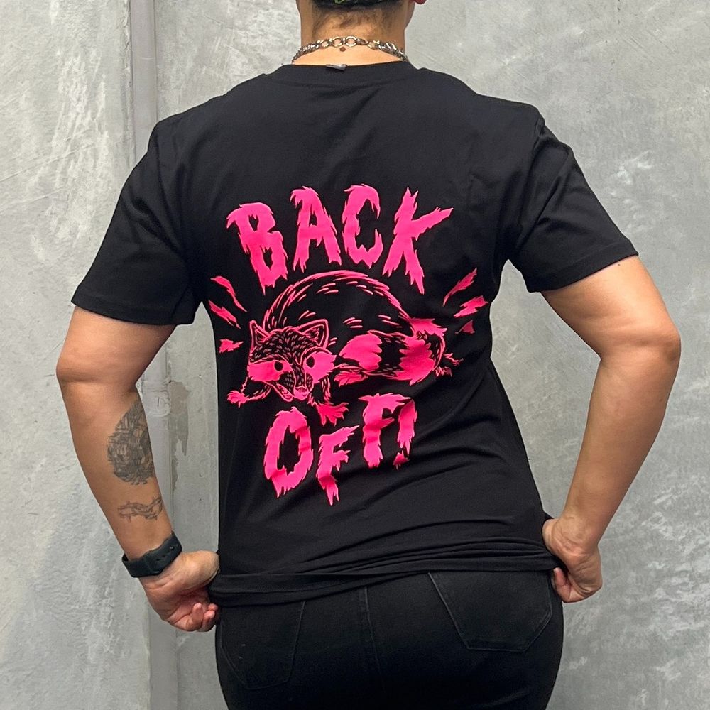 A black t-shirt with a hot pink angry raccoon on the back, it says Back Off! 