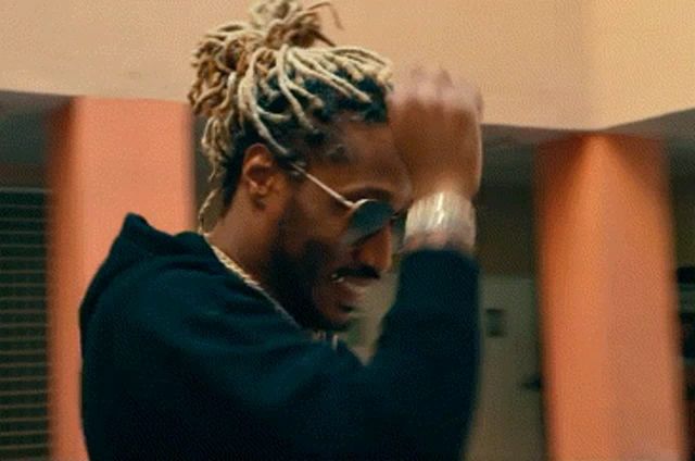 a man with dreadlocks and sunglasses is wearing a black hoodie