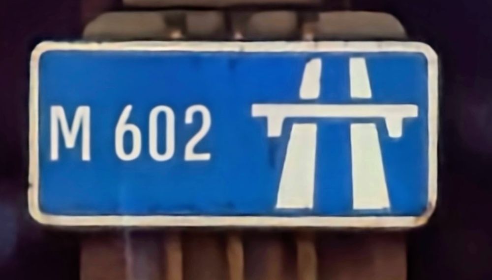 A start of motorway sign on the M602 showing a weirdly large gap between carriageways in the motorway symbol.