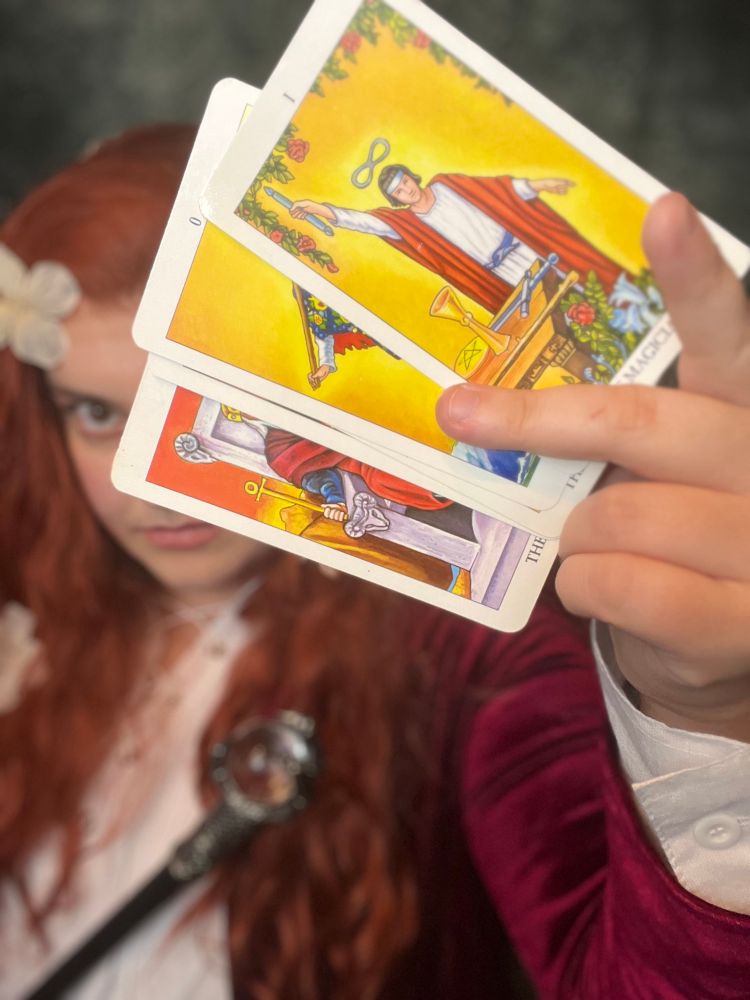 Me cosplaying Brian Froud’s Magician painting with a handful of major arcana tarot cards prominently displayed, the Magician card in front