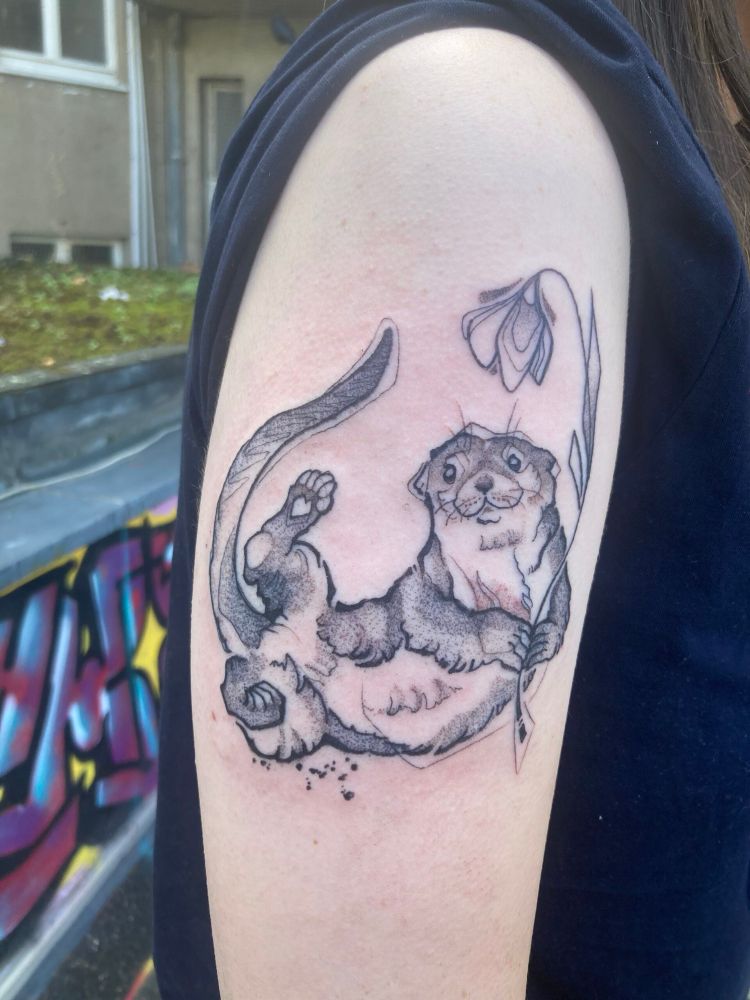Illustrative tattoo of an otter holding a flower