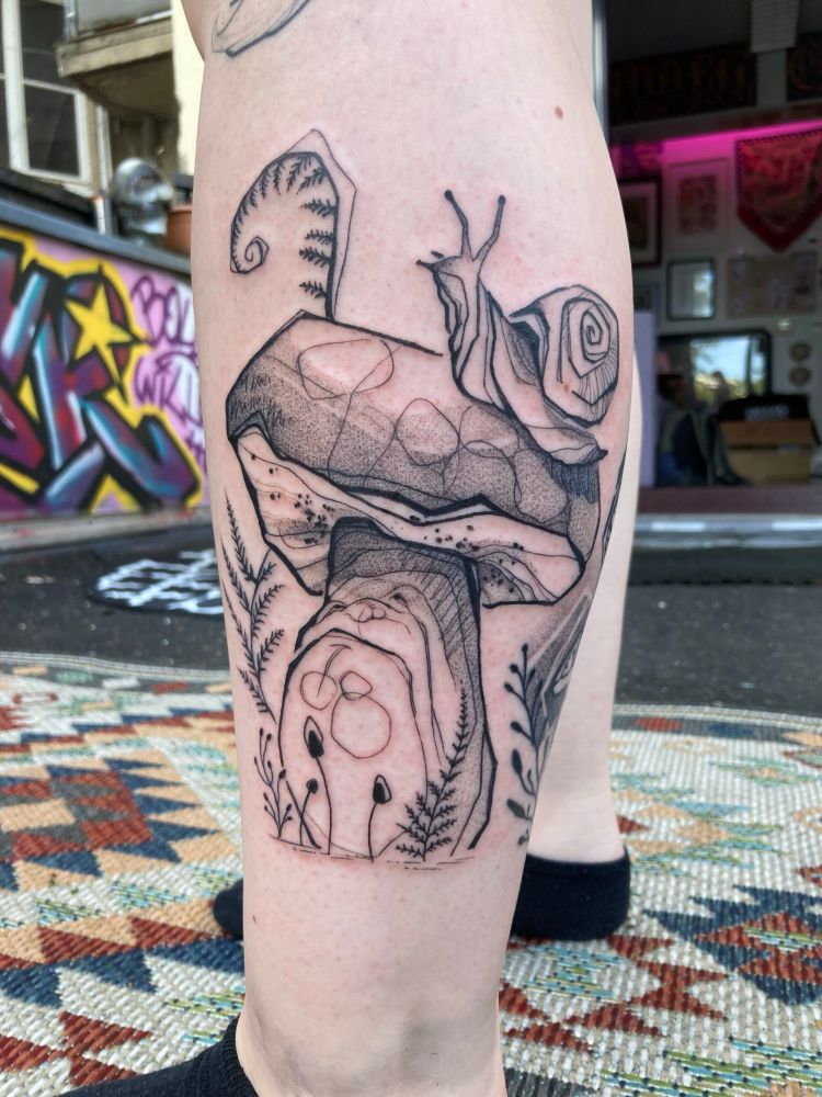 Tattoo of a mushroom with a snail on its cap, looking grumpily at the snail