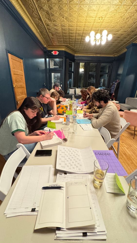 nine happy and productive goal-setters, busy writing at a long table in a beautiful event space 🥰