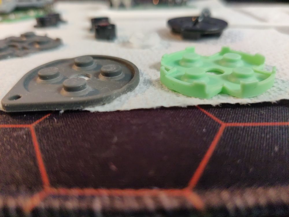 Picture of SN30 pro silicone pad next to a PS2 one, but after the PS2 one has been cut to fit into the SN30 pro's case. The PS2's pad needed a V-shaped section of the lip removed in order to fit into the circular section of the SN30