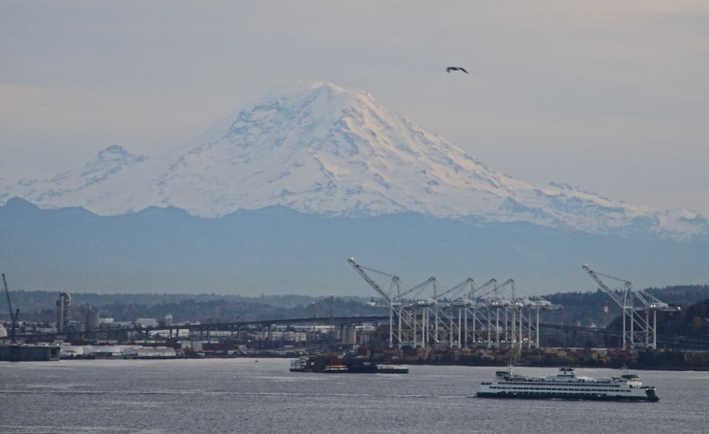 Mount Rainier, seen across the sound. A ferry and the Seattle industrial district in the foreground.