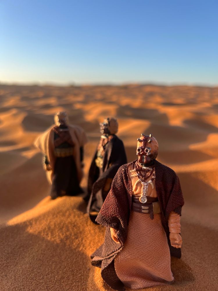 Several Tusken action figures gathered in the sand. Extra good lighting. 