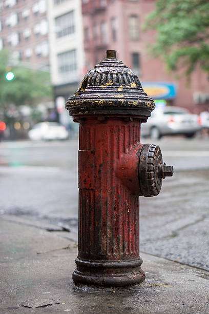 Old-style US fire hydrant with ribbed body and cap, peeling paint and a general air of having seen better days.