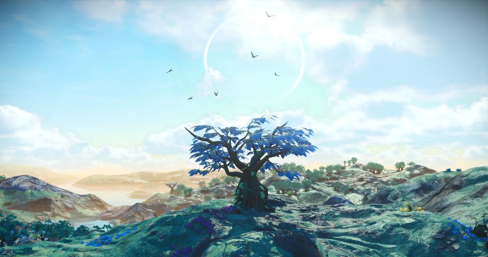 A screenshot from the videogame, "No Man's Sky." It shows an earth-like landscape with blue skies and greenish foliage. In there center of the landscape, a massive tree stands tall. Birds flutter around is wide, blue leaves, and the faint outline of a planet can be seen in the daytime skies above. In the distance, a few lakes lie between the hills amid a golden haze.