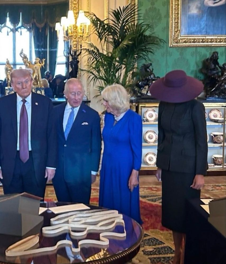 The orange idiot next to old royals. Melania is hiding under a hat. 
