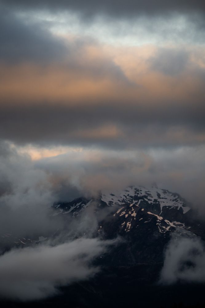 A picture of a sunrise over a mountain with a heavily cloudy sky.