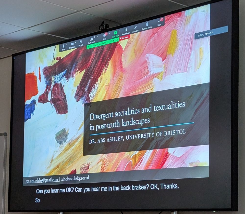 Photo of PowerPoint slide with colorful abstract pattern and title reading "Divergent socialities and textualities in post-truth landscapes" by Dr Abs Ashley, University of Bristol 