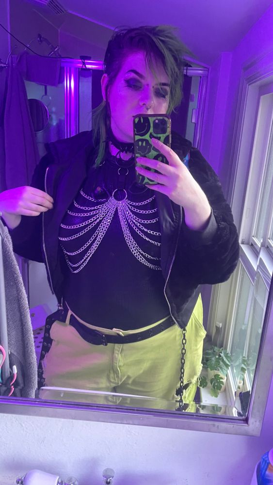 Mirror selfie of me wearing croc print shiny body suit + chain chest harness + lime green plants with fluffy coat!