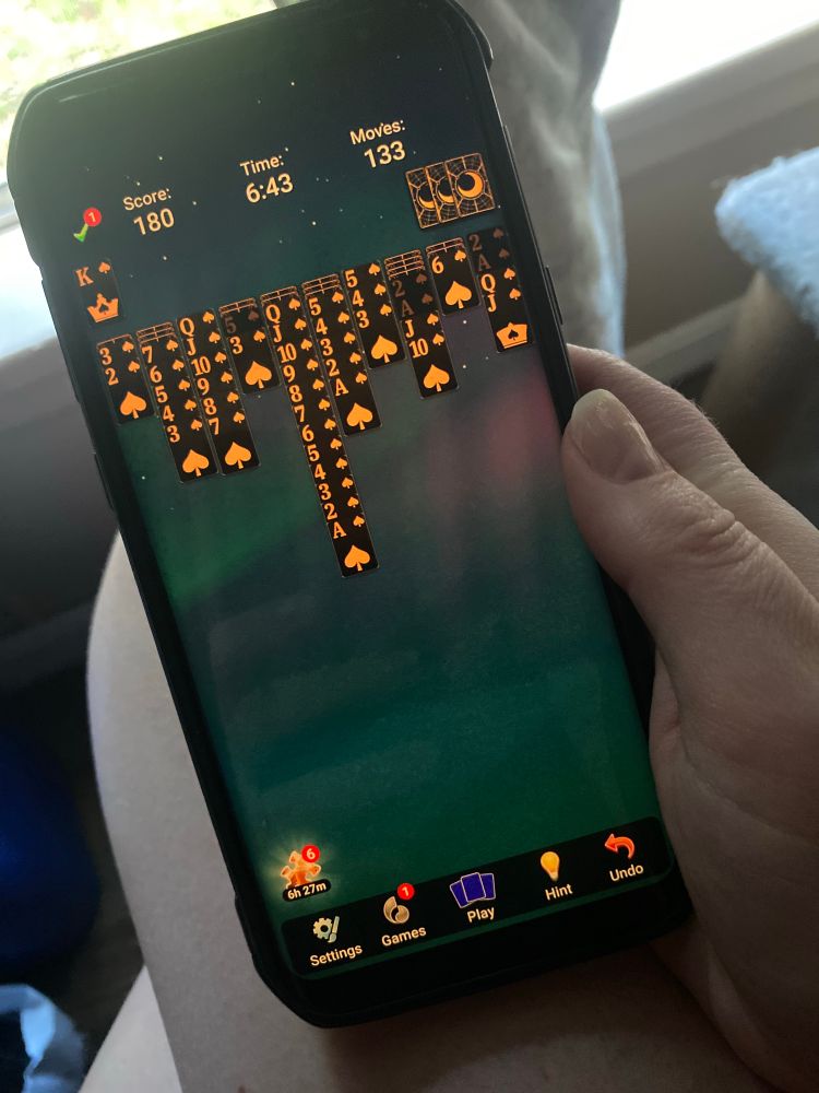 A photo of my hand holding my alt phone, i’m playing spider solitaire.