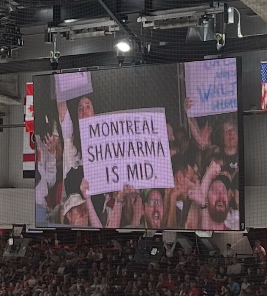 A fan holds up a sign at a hockey game on screen that reads “Montreal shawarma is mid.”
