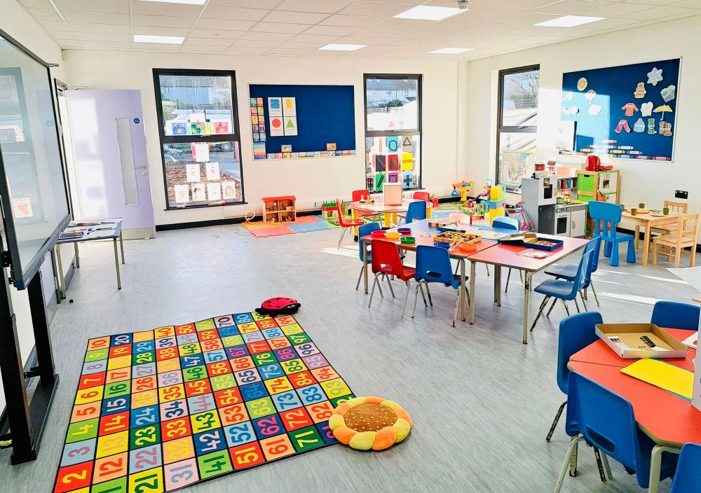 Inside our new school building. A big, bright airy room, with children’s drawings and Irish words on the wall, some little tables and chairs, and the room laid out for a pre-school day. 