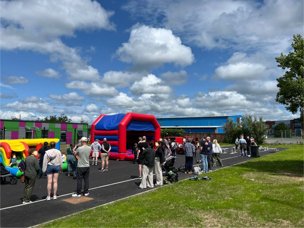 Fun day at Scoil na Seolta with grass bank, bouncy castles and people milling around. 