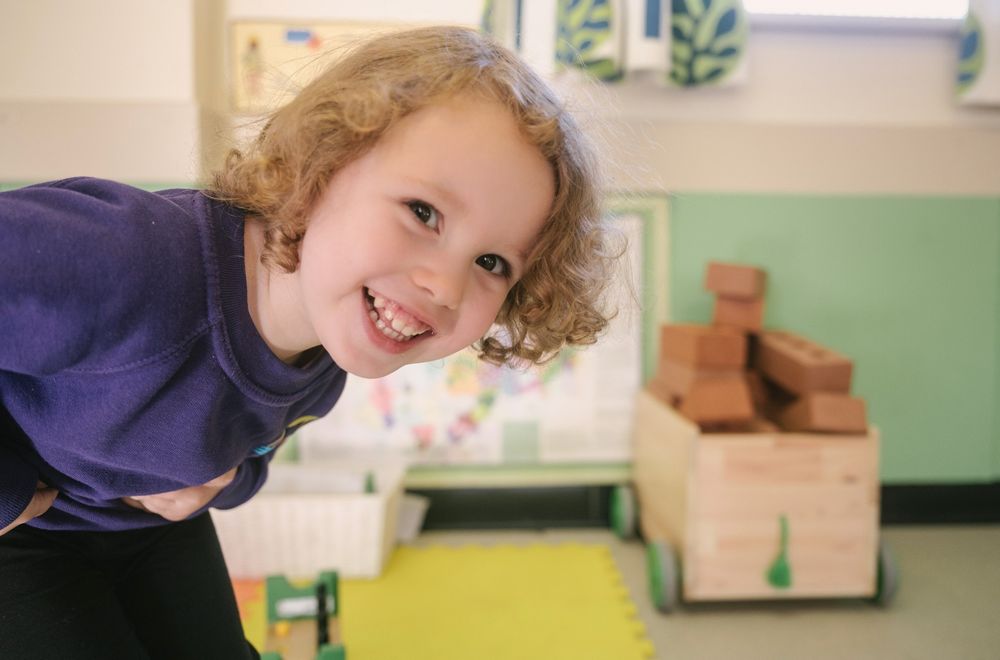 One of the children from Naíscoil na Seolta in the classroom. She is looking out at the camera, as if to invite people in.