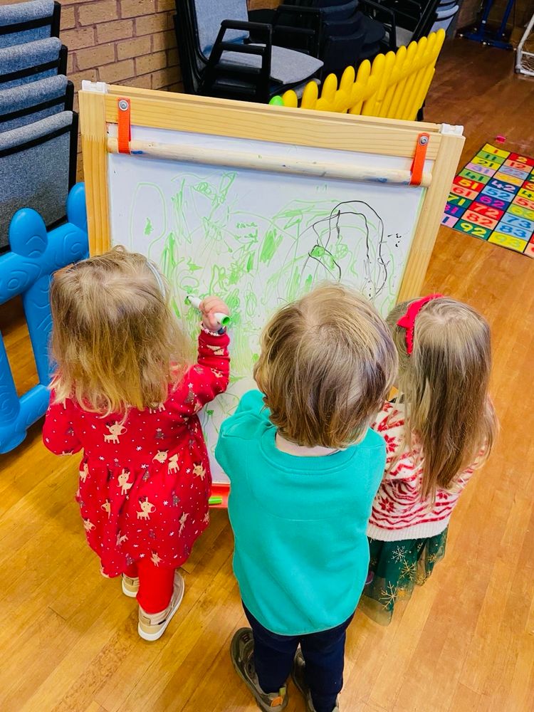 Christmas party at Naíscoil na Seolta. Some of the kids drawing on paper on an easel. 