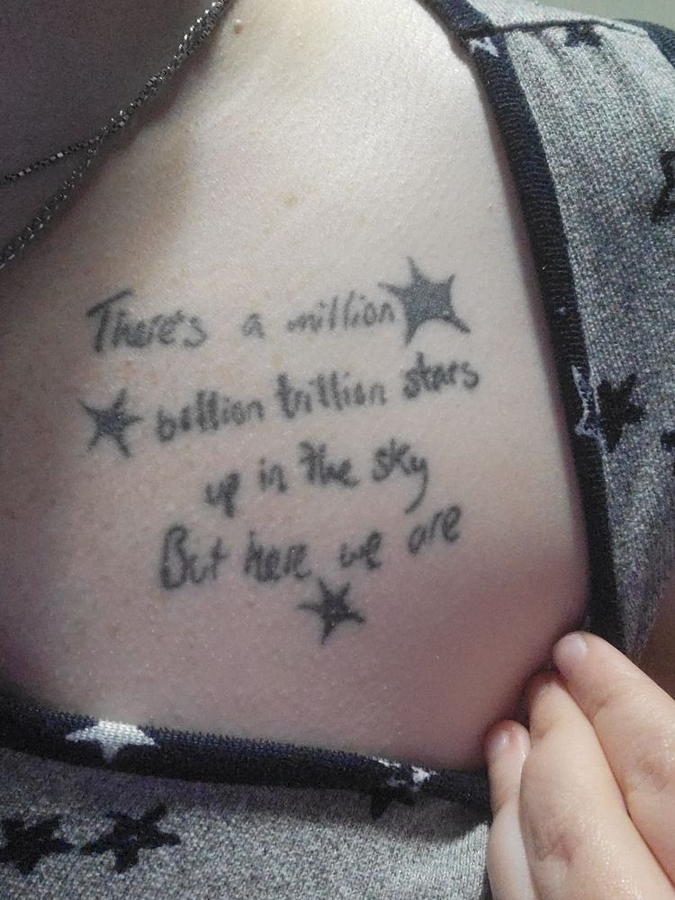 A tattoo on my chest entirely in black that reads "There's a million billion trillion stars up in the sky but here we are" with a few black stars around it