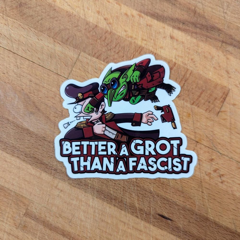 A sticker of a small goblin punching a commisar from Warhammer 40k in the face with the text "better a grot than a fascist" written under it.