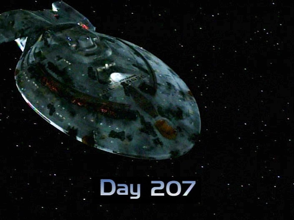 The USS Voyager, an Intrepid-class starship floating through space. Voyager has an ovoid shaped primary hull which keeps her secondary hull out of sight. Her primary hull is covered with scars and is missing some of the plating. There is a prominent orange scar on her starbord side just beneath the ventral phaser array where the plasma conduits on deck five exploded. Superimposed on the image is the text "Day 207"
