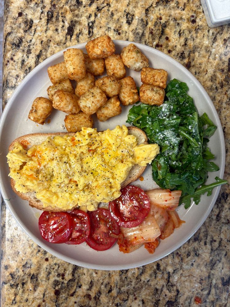 soft scrambled eggs with chili oil and herbs on toast with tater tots, arugula, kimchi, and tomatoes. the eggs didn't burn, please clap.