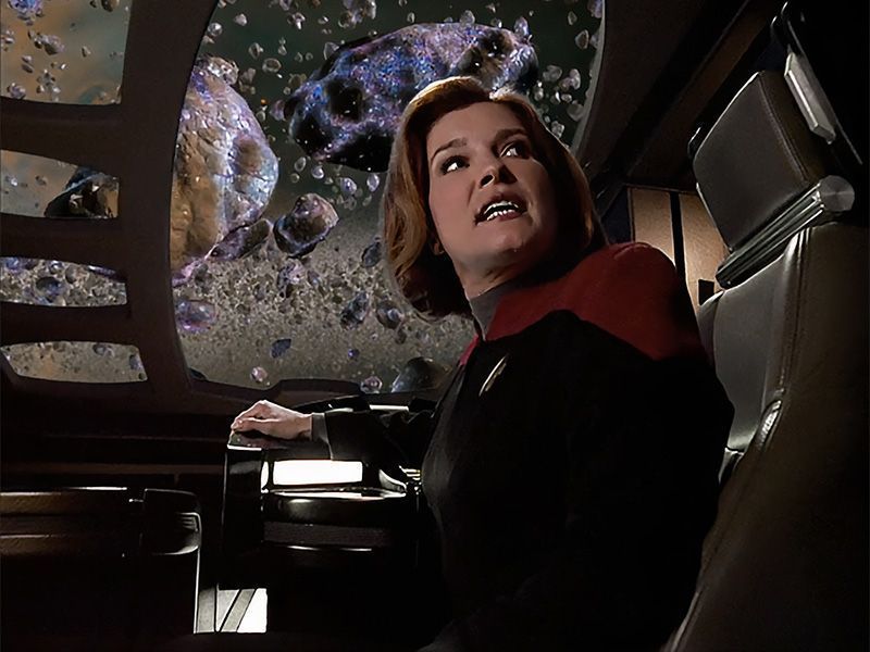 Captain Janeway, played by Kate Mulgrew, in Star Trek: Voyager season 6 episode 20 "Good Shepherd." She is seated in a shuttle, giving orders in the middle of an asteroid field. 
