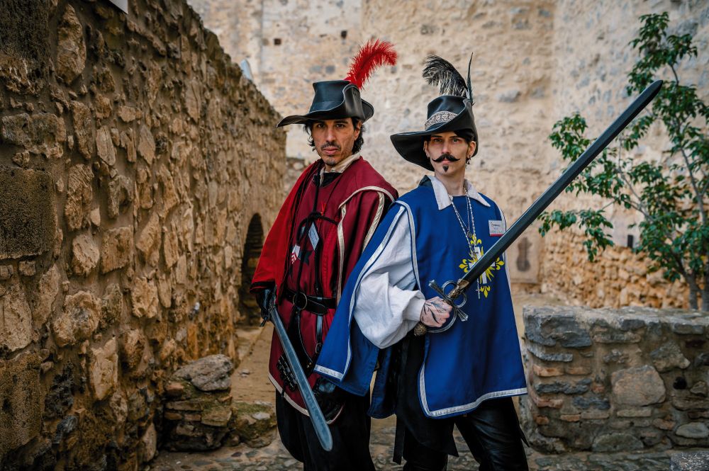 Rochefort and a sort of Aramis holding swords at a Three Musketeers Larp.